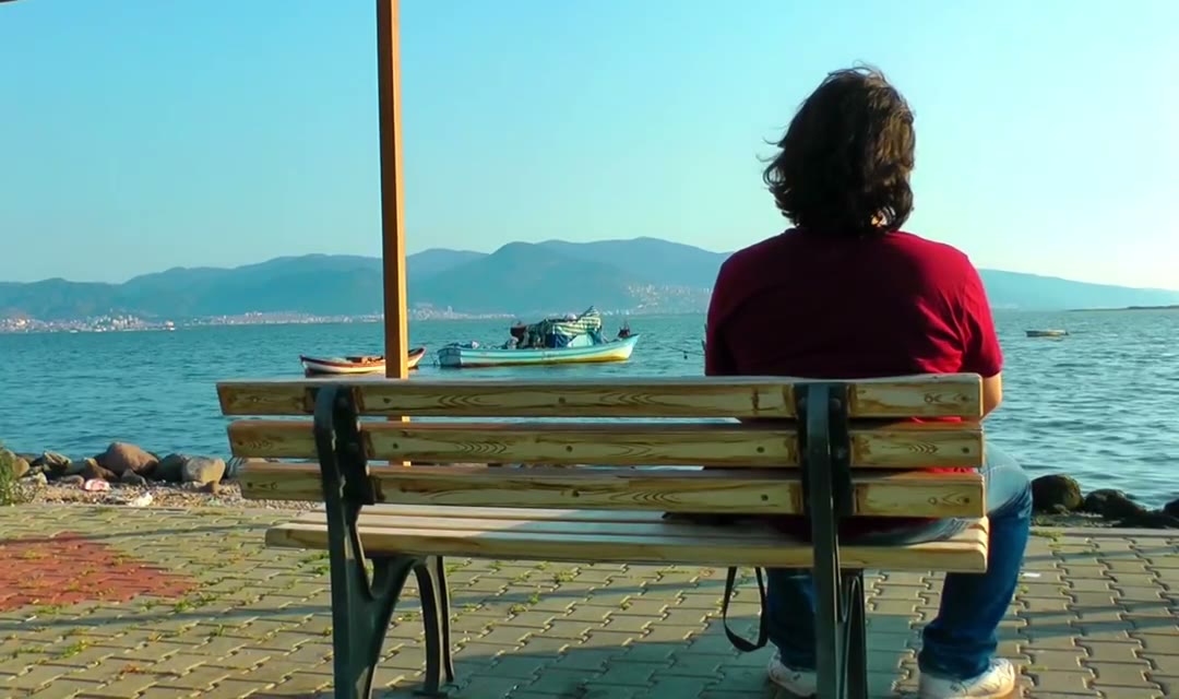 Pensive man looks at the sea from a bench
