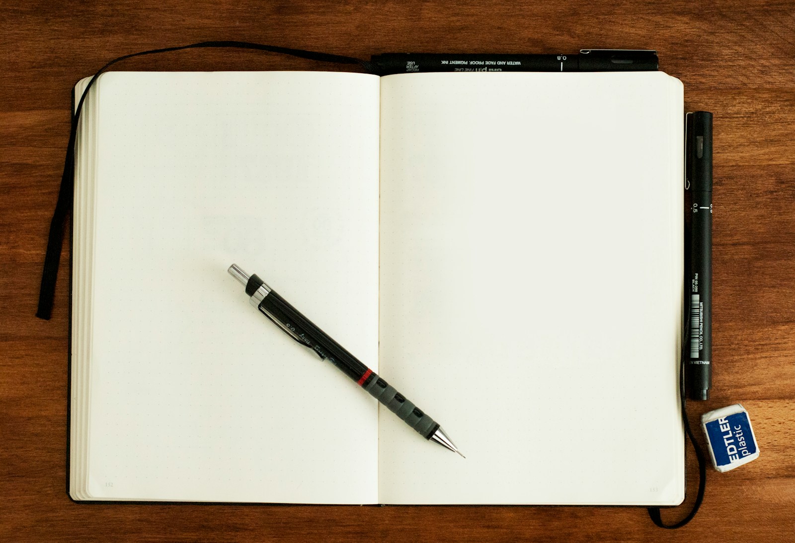 An open cream-colored notebook with a pen laid diagonally across it.