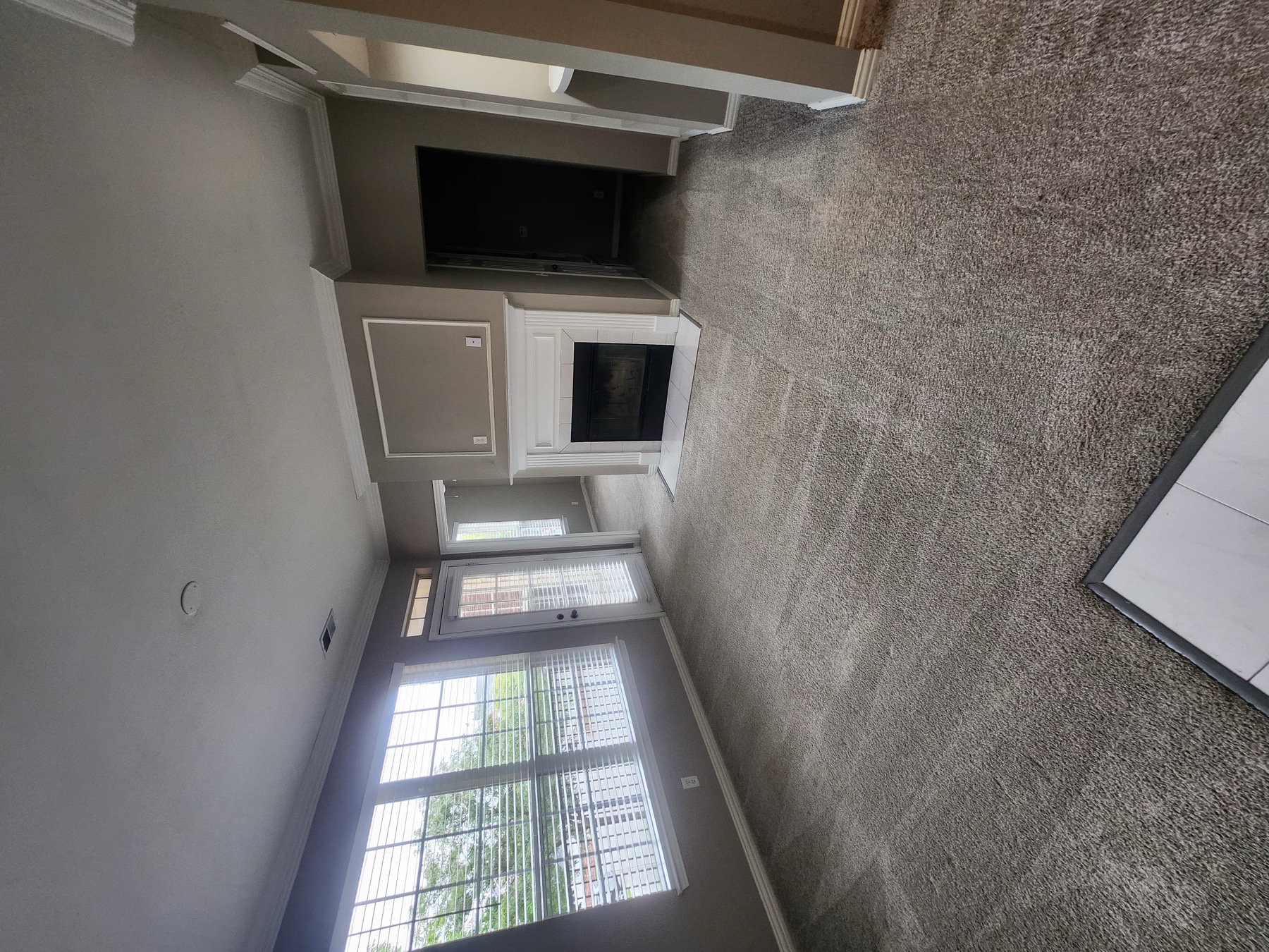 Vacuumed living-room carpet, window blinds and a white fireplace in the Lincoln home