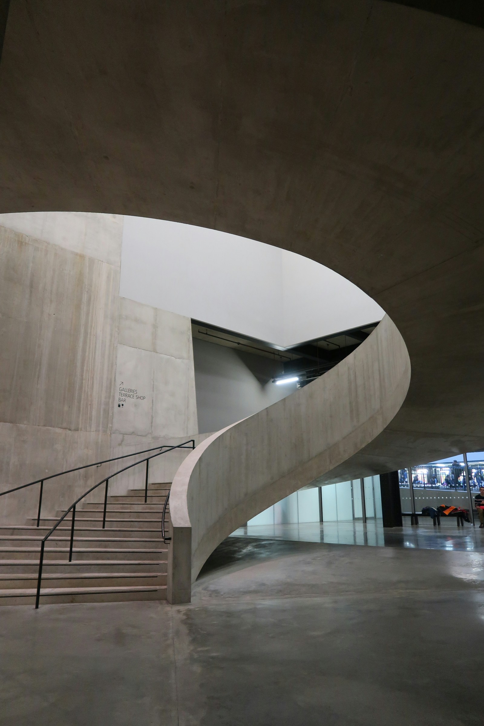 A curved concrete stairway inside a spacious modern building.