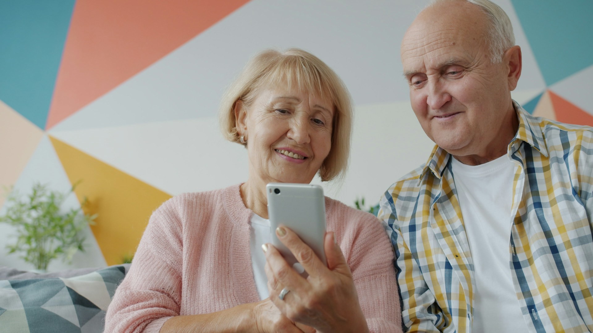 Senior couple looking at a phone together at home