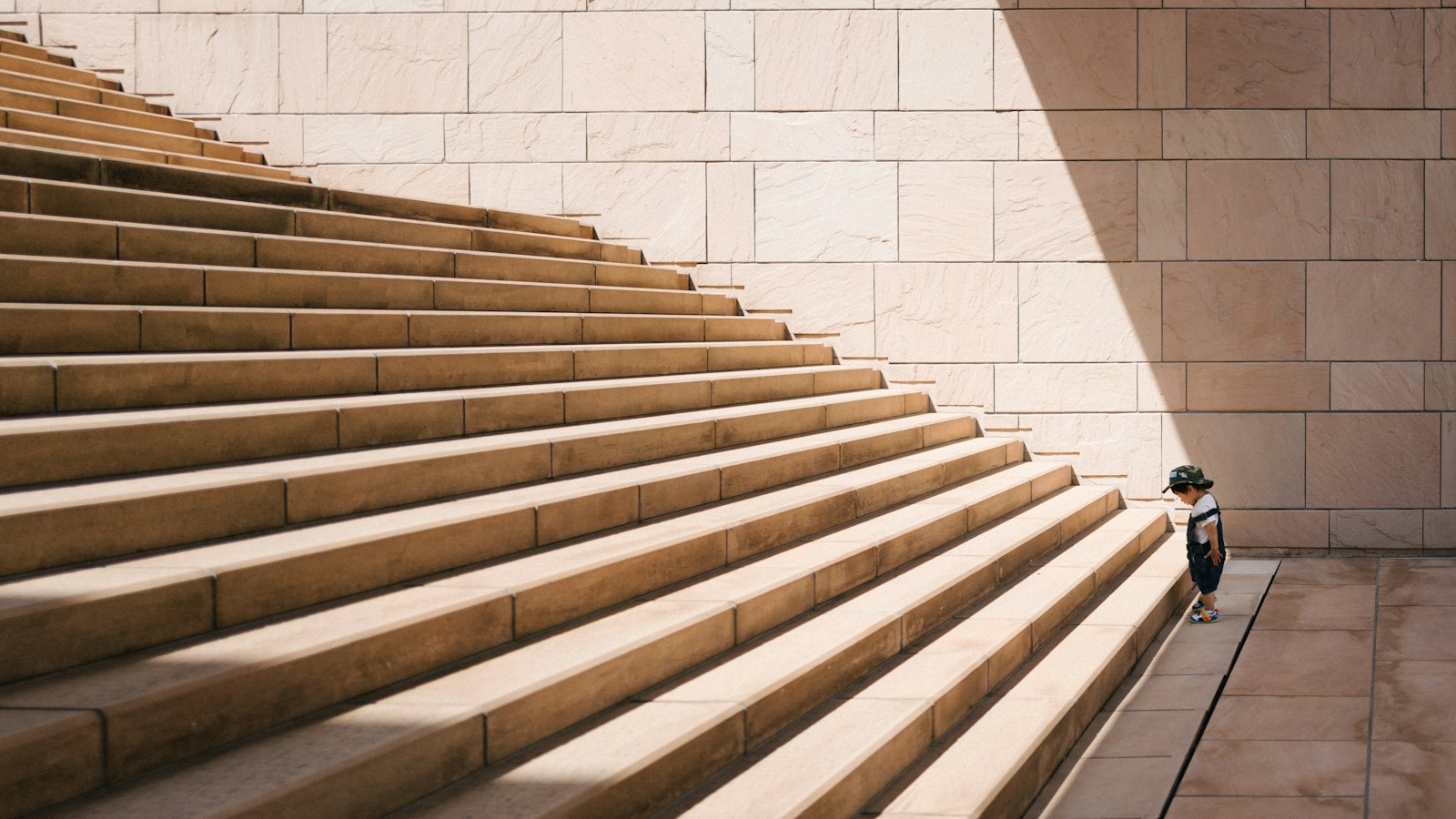 A broad stone staircase with one small figure climbing at the edge.
