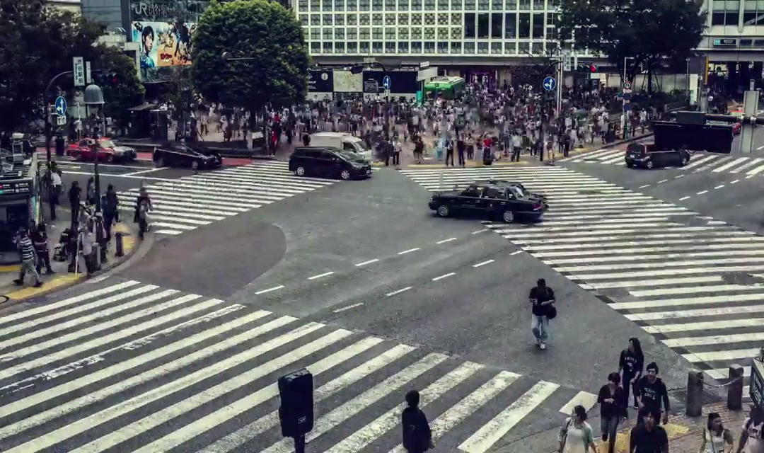 Crowds of people cross a street junction