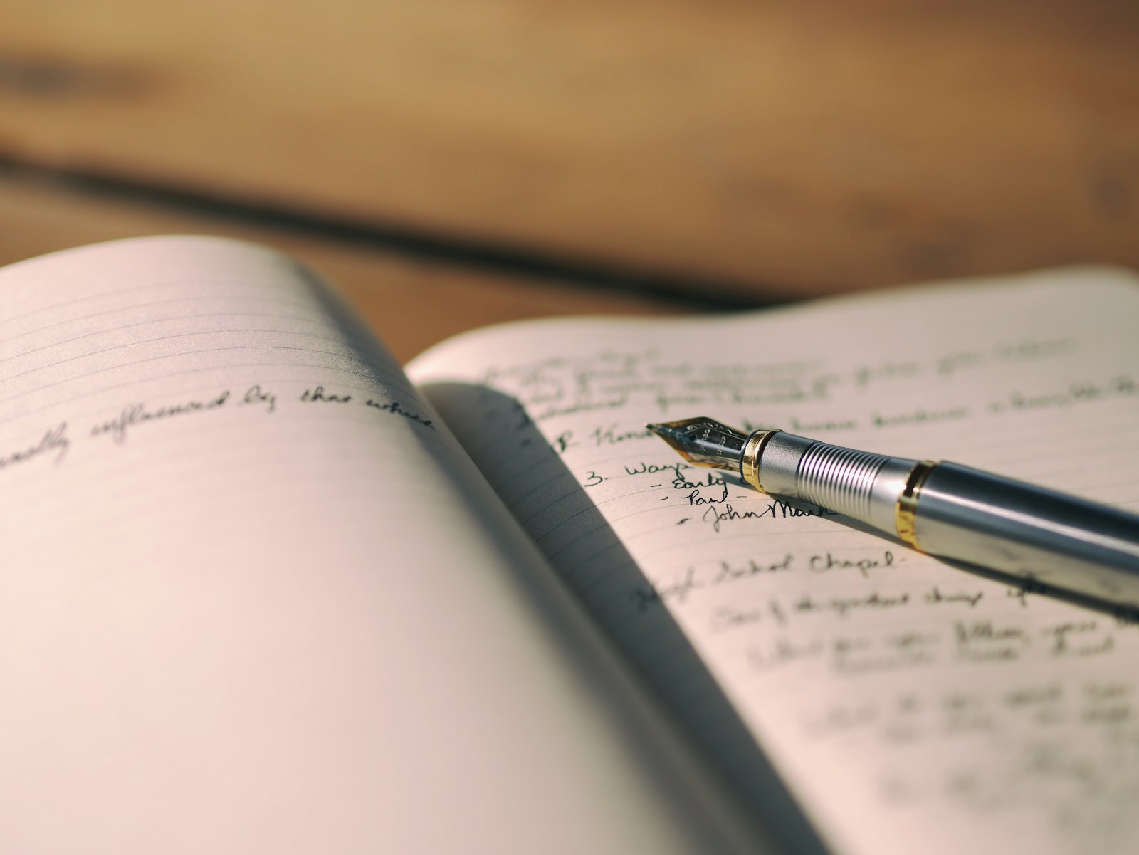 A fountain pen resting across handwritten journal pages.