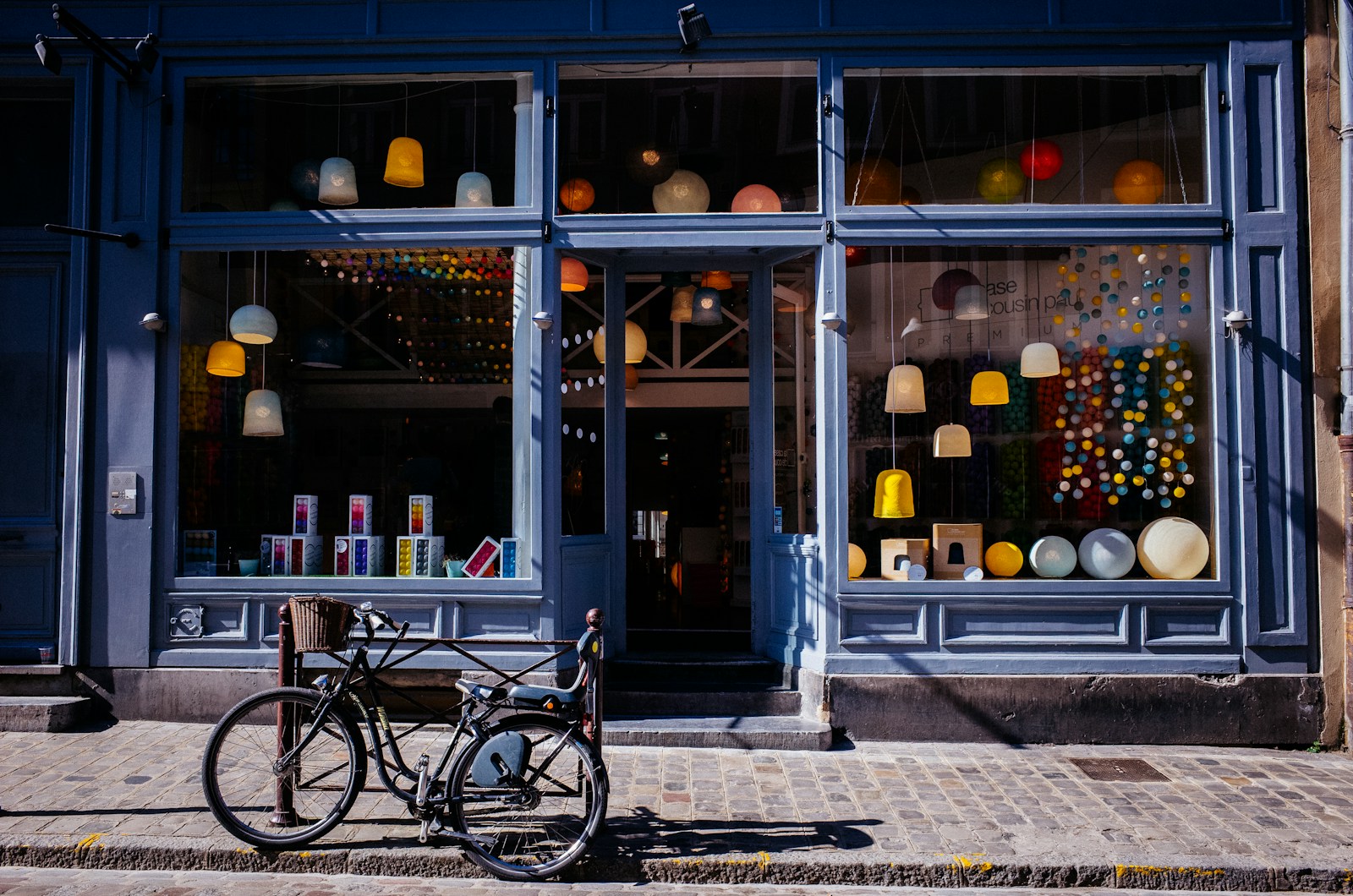 A blue storefront with a bicycle parked outside its display window.
