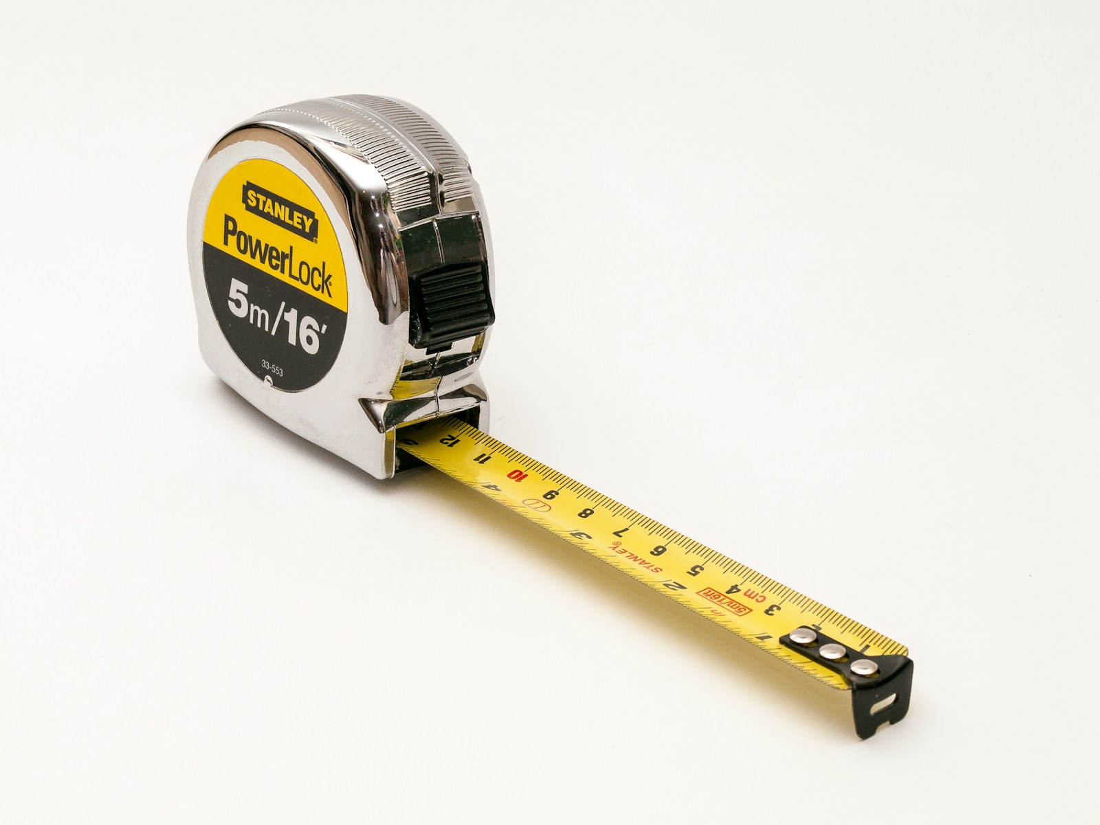 A retractable metal tape measure extended across a plain surface.