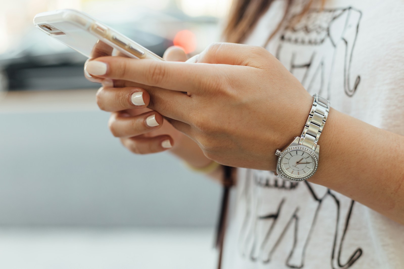 Close-up of hands using a white smartphone.