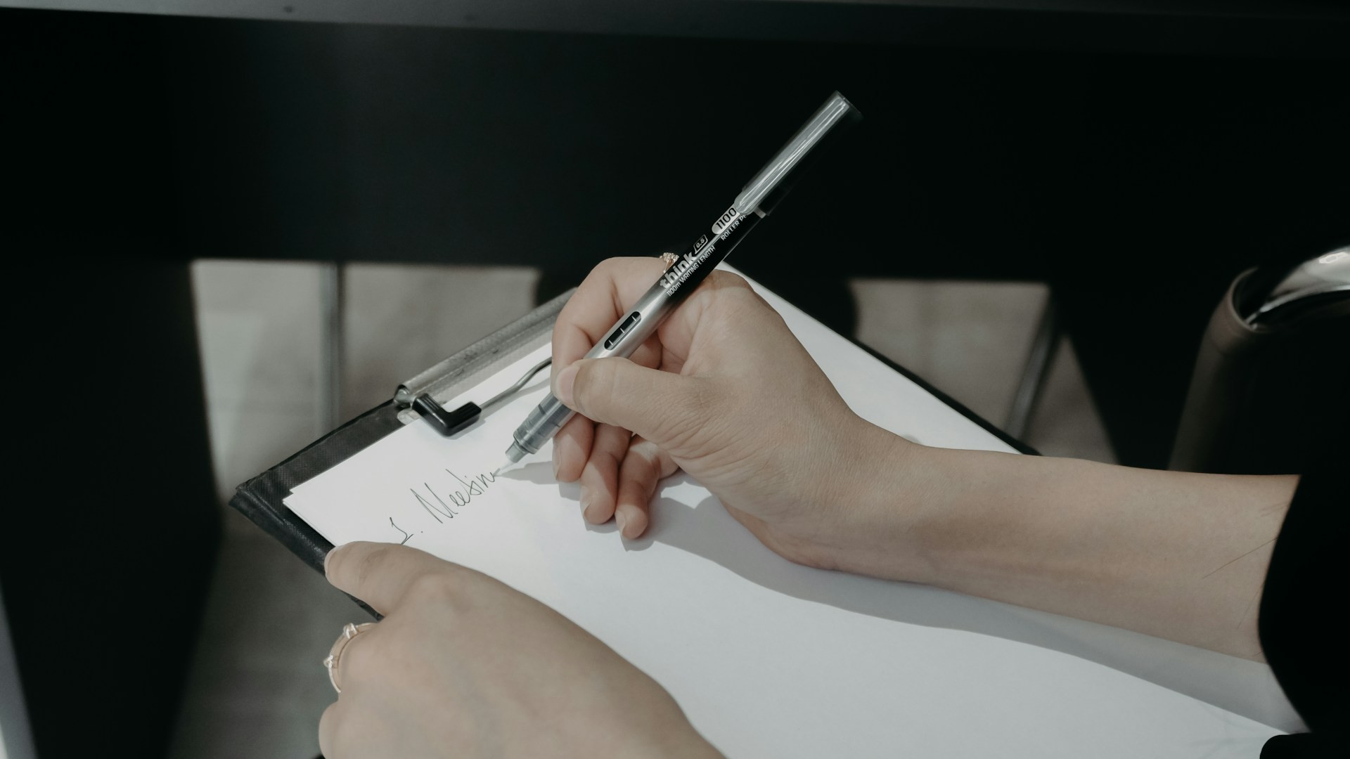 Hand writing notes on a clipboard