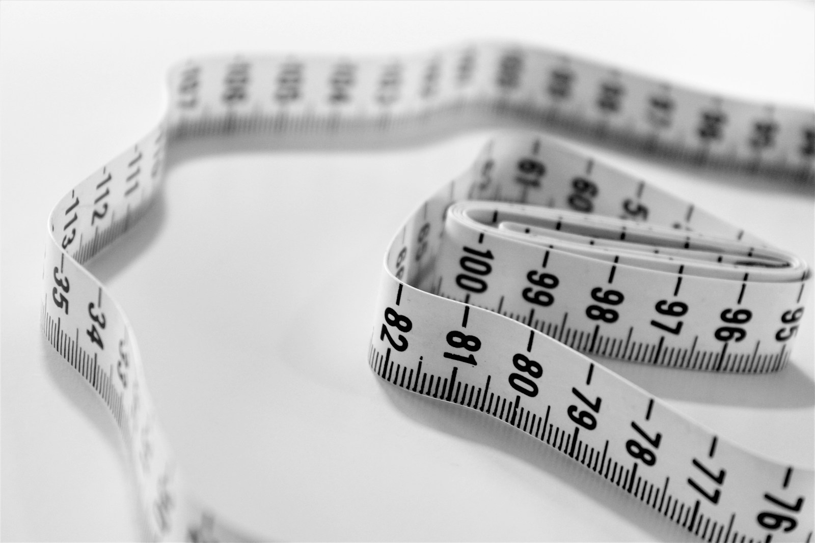 A black-and-white flexible measuring tape folded on a light surface.