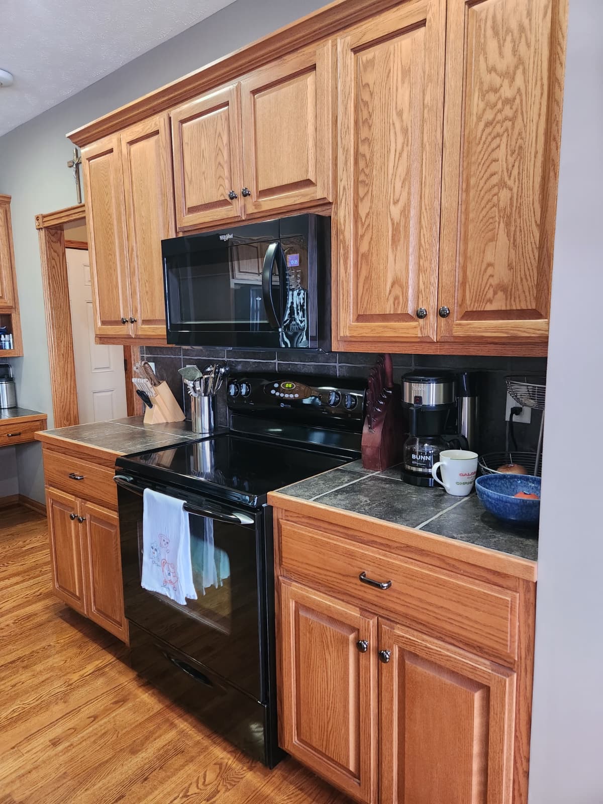 Oak cabinets, tile counters and a black range in the freshly cleaned kitchen