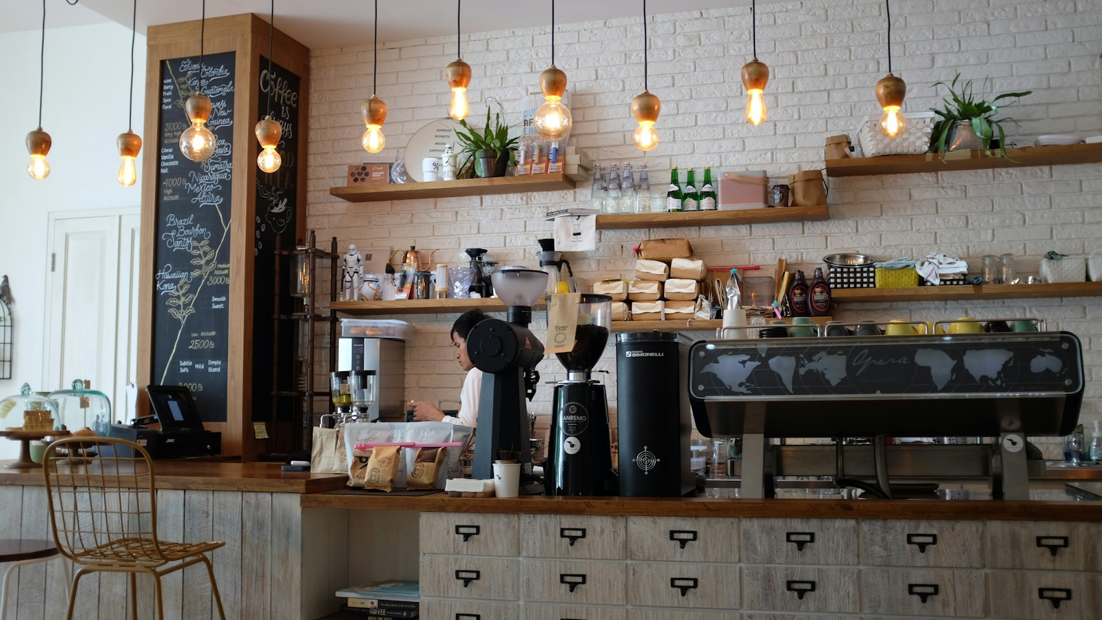 A cafe counter with coffee equipment and shelves in warm natural light.