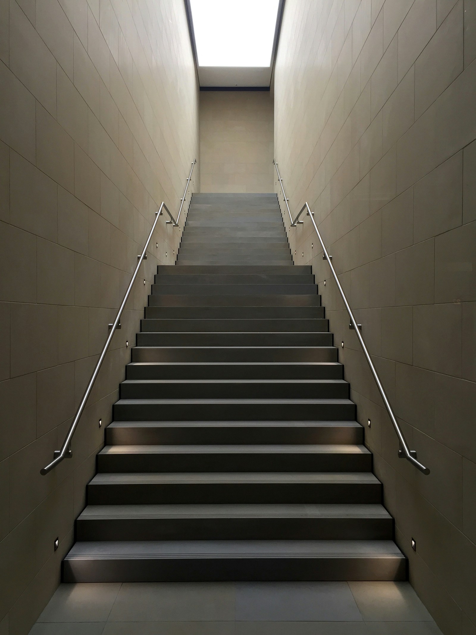 A narrow staircase rising toward daylight between plain walls.