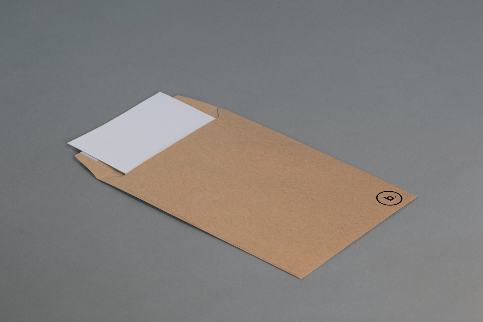A plain tan envelope with a white card partly tucked inside on a gray surface.