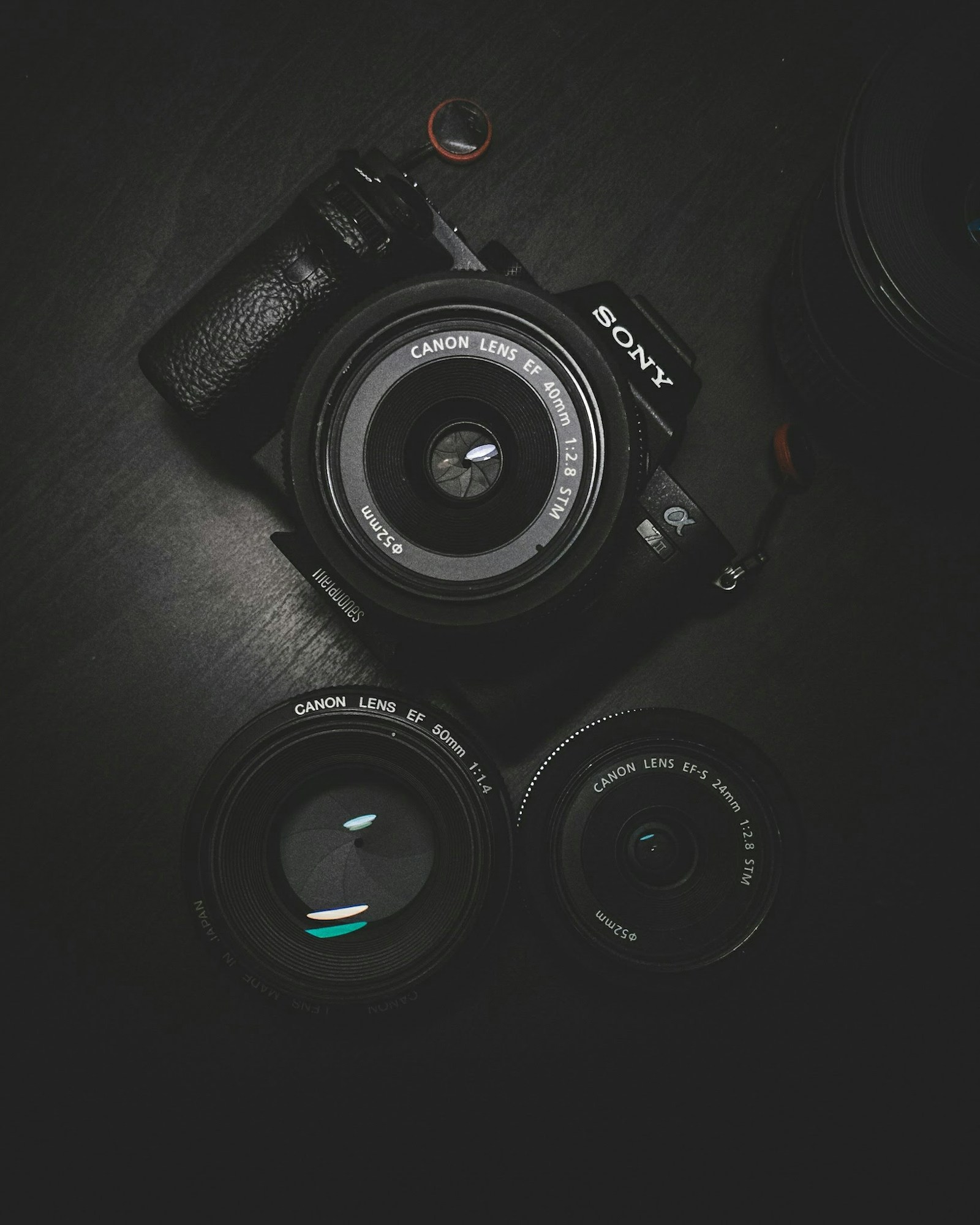 A camera body and two lenses arranged on a dark surface.
