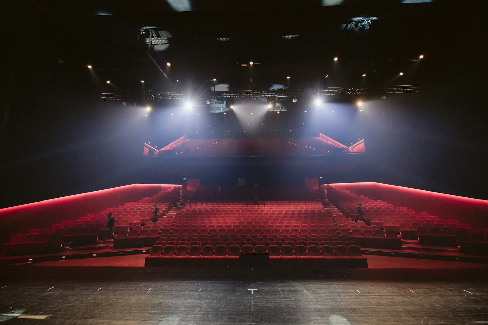 Rows of red theater seats facing a lit stage.