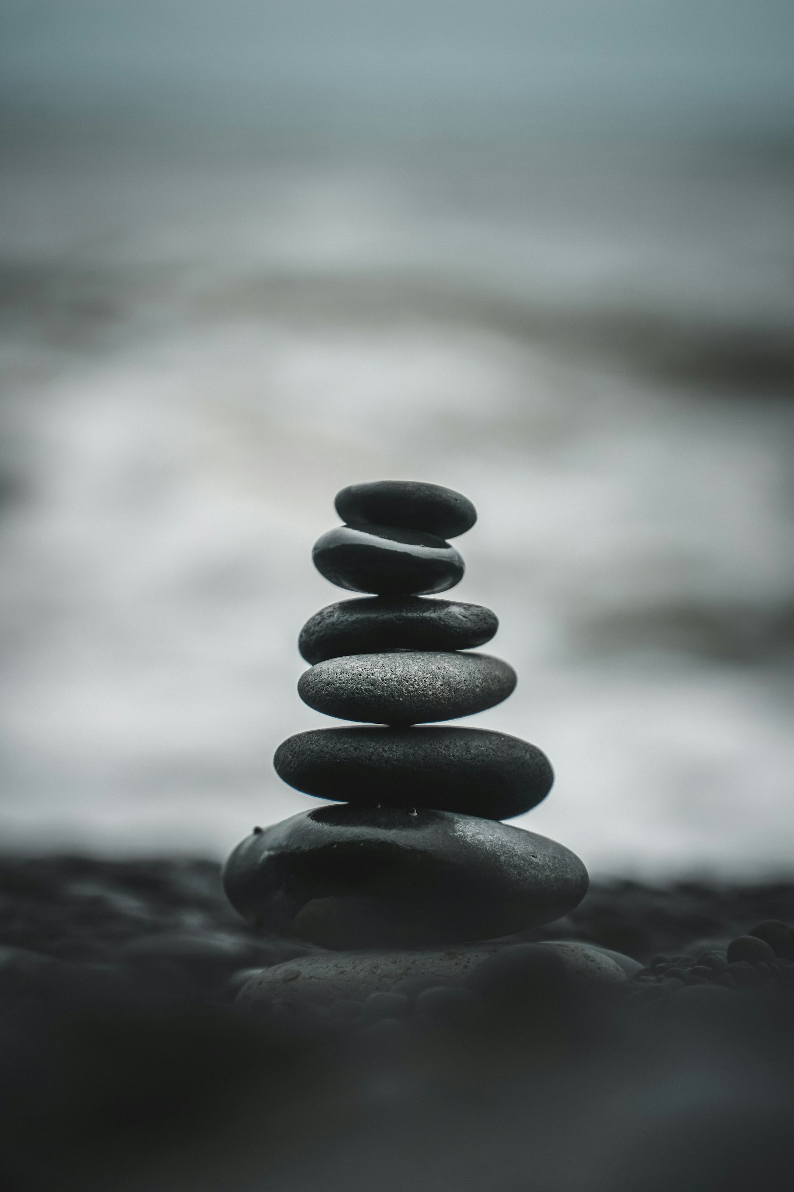 A small stack of smooth stones balanced beside softly blurred water.