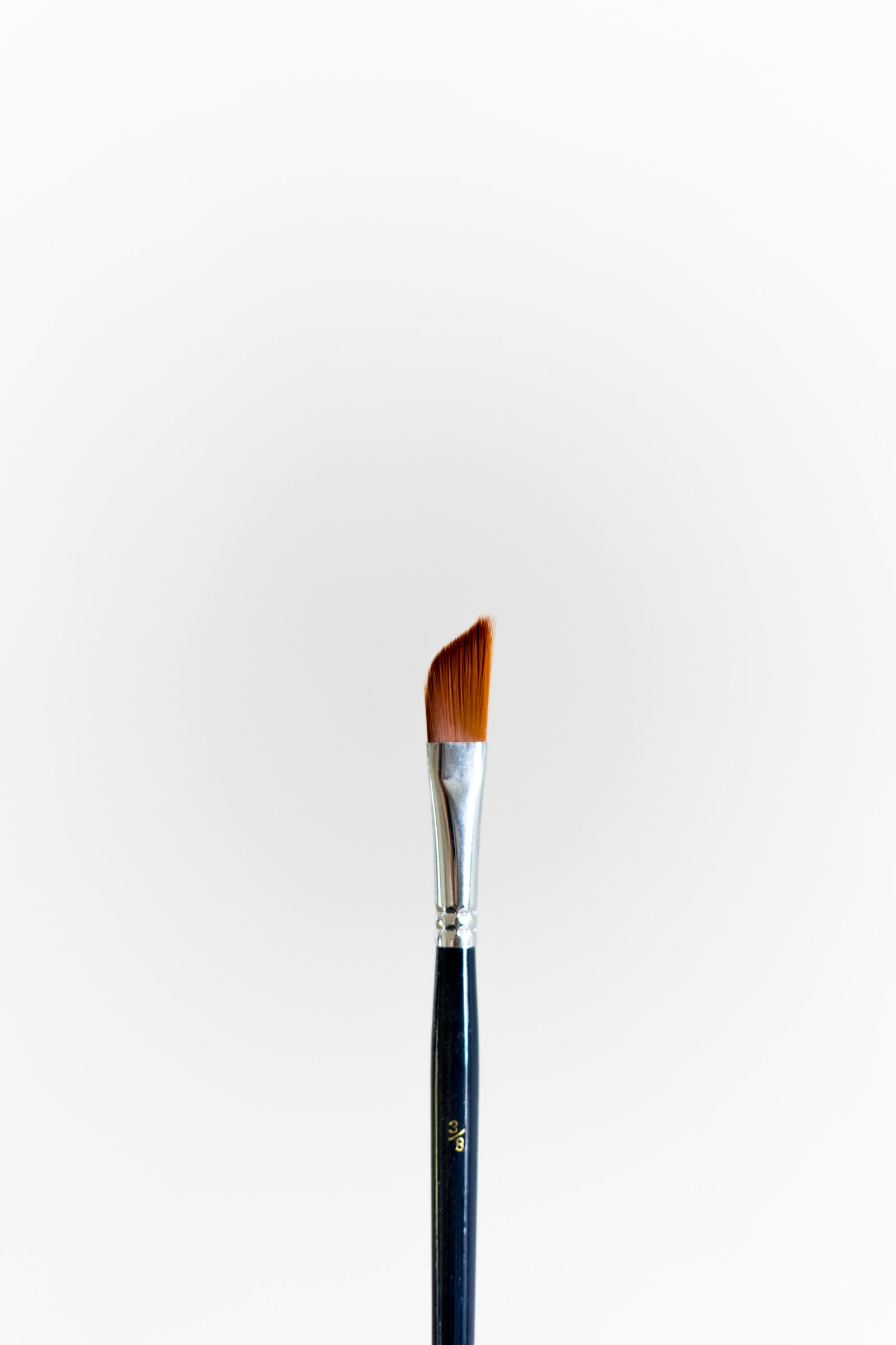 One slim paintbrush standing against a plain white background.