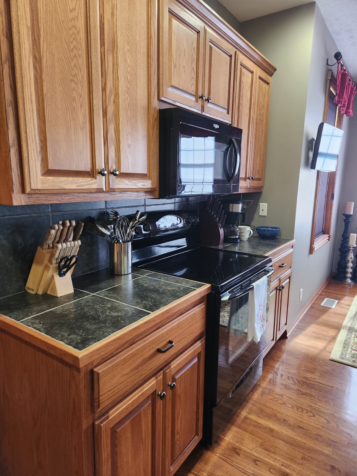 Black range and microwave surrounded by oak cabinetry and tile counters